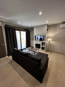 a living room with a black couch and a tv at Giannel Luxury Apartment 1 in Kastanéa