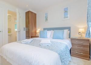 a bedroom with a large white bed with blue pillows at Cherry Tree Lodge in Narberth