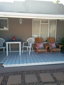 a porch with two chairs and a table and a table and benches at @Echeveria in Montagu