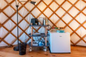 a room with a refrigerator and two shelves in a yurt at Awaawa - Rangi Yurt in Palm Beach