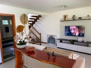 ein Wohnzimmer mit einem Sofa und einem TV in der Unterkunft CASA PRAIA DO FORTE in Mata de Sao Joao