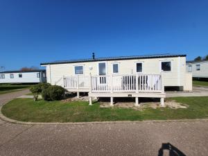 a white mobile home with a porch and a house at Parkdean Kessingland Beach Holiday Chalet in Benacre