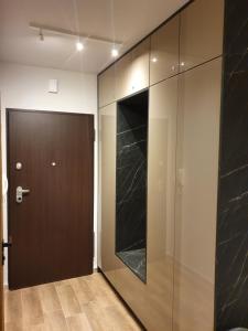 ein Flur mit einer braunen Tür und einer Glaswand in der Unterkunft APARTAMENT W CHMURACH- 15 PIĘTRO OSIEDLE TYSIĄCLECIA- parking w hali garażowej, wielki taras z widokiem na zachód słońca in Kattowitz + 33 Fotos