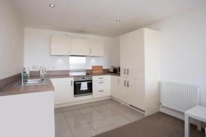 a white kitchen with white cabinets and a sink at Stunning 2 Bedroom Apartment in Ashley Down with Cricket View in Bristol