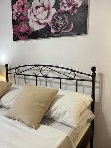 a black bed with white pillows and a painting on the wall at Apartman IVA, Donji Miholjac in Donji Miholjac