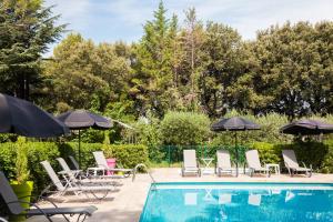 una piscina con sillas y sombrillas junto a una piscina en Le Petit Manoir Logis, en Les Angles