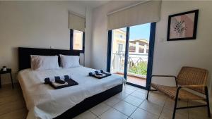 a bedroom with a bed and a chair and a window at Maria's Holiday House - Communal Pool in Paphos City