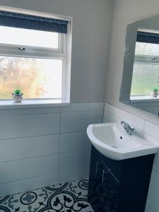 een badkamer met een wastafel en een raam bij Atlantic Bay Cottage in Culdaff
