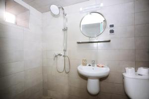 a white bathroom with a sink and a mirror at Hotel Al Arboussas in Essaouira