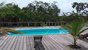 a swimming pool on a wooden deck with a chair at Amazon Boto Lodge Hotel in Careiro