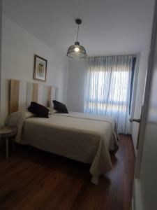 - une chambre avec un grand lit dans une pièce dotée d'une fenêtre dans l'établissement Apartamento 6 personas Playa de Covachos, à Soto de la Marina