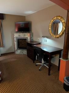 a room with a desk and a television and a fireplace at Red Roof Inn & Suites Detroit - Melvindale/Dearborn in Melvindale