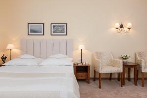 a bedroom with a large white bed and a chair at Villa Sedina in Rewal