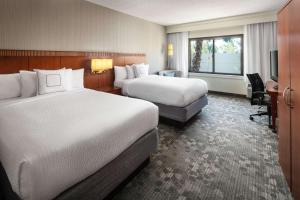 a hotel room with two beds and a television at Sonesta Select Laguna Hills Irvine Spectrum in Laguna Hills