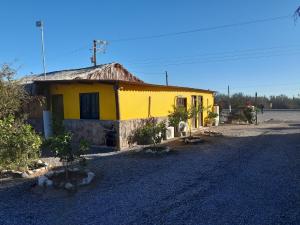 uma casa amarela ao lado de uma estrada de terra em Loreto La Regional em Loreto