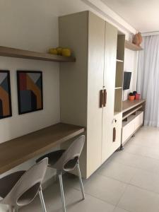 une cuisine avec un bureau, deux chaises et une armoire dans l'établissement Flat Eco Resort Praia Dos Carneiros PE, à Tamandaré