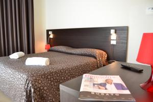 a hotel room with a bed and a magazine on a table at Hotel Morena in Lido di Jesolo