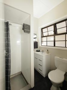 a white bathroom with a toilet and a shower at Riverlodge Motel in Nelson