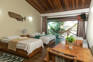 a room with two beds and a table and a window at Pousada e Restaurante Mangue Seco Angra in Angra dos Reis +130 photos