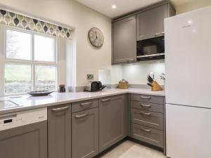 a kitchen with gray cabinets and a white refrigerator at The Nook Bank Newton in Bell Busk