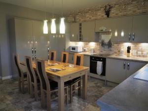 a kitchen with a wooden table and chairs at Valhalla Brae, 3 Bed House on NC500 with Beautiful Castle and Sea Views in Keiss