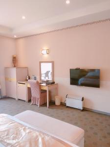 een slaapkamer met een bureau en een computer aan de muur bij Mi Jing Garden Spring Resort in Wulai