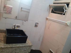 a bathroom with a black sink and a tiled wall at Ape agradável a 50 m das piscinas de Piratuba in Piratuba