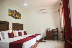 a hotel room with two beds and a table at Divine Villa in Anuradhapura