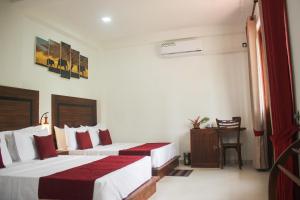 een hotelkamer met 2 bedden en een tafel bij Divine Villa in Anuradhapura