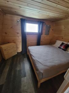 1 dormitorio con 1 cama en una cabaña de madera en Motel Le Riviera, en La Malbaie