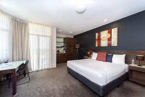 a bedroom with a large bed and a desk and a desk at Sfera's Park Suites & Convention Centre in Adelaide