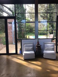 two white chairs in a room with large windows at El bosque serrano in Sierra de los Padres +3 photos