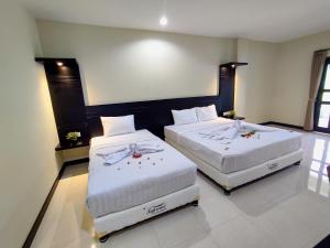two beds in a hotel room with white sheets at Crystal City Hotel in Mataram