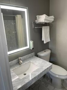 a bathroom with a sink and a toilet and a mirror at Villa Court Inn Oroville in Oroville