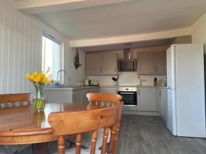 a kitchen with a wooden table and a white refrigerator at Maes Y Coed in Pwllheli