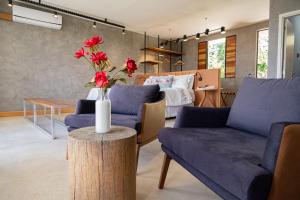 a living room with two blue couches and a table with flowers at Fazenda Pedra Lisa Hotel Boutique in Brumadinho