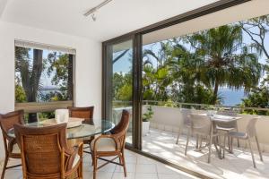 a dining room with a glass table and chairs on a balcony at Cove Point Apartment 1, Little Cove in Noosa Heads