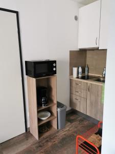 a small kitchen with a microwave and a sink at Joli Appartement 2 pièces 4 voyageurs tout équipé 13 avenue de la Divette 14390 CABOURG in Cabourg
