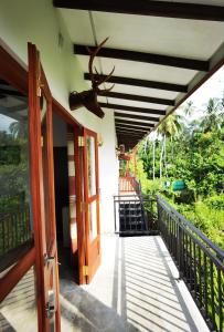 une terrasse couverte d'une maison avec une porte et un bois dans l'établissement Turtle Lamp, à Unawatuna