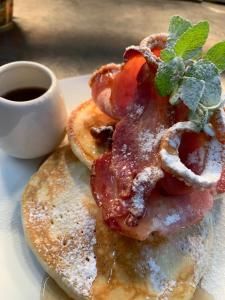 a plate of pancakes with bacon and a cup of coffee at The Waterfront Wynyard in Wynyard