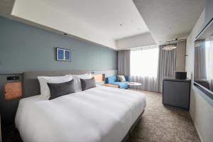 a bedroom with a large white bed and a blue chair at NOHGA HOTEL KIYOMIZU KYOTO in Kyoto