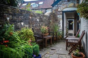 einen Garten mit Bänken und Pflanzen und einer Steinmauer in der Unterkunft The Moda House in Chipping Sodbury