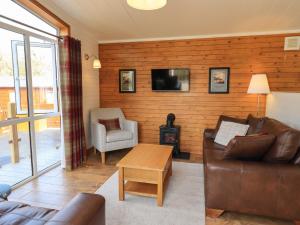 a living room with a couch and a wood wall at Ramblers' Rest Lodge in Windermere