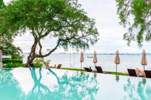 a swimming pool with umbrellas and chairs next to the water at Centara Sonrisa Residences & Suites Sriracha in Si Racha