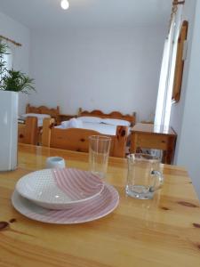 a wooden table with a plate and two glasses on it at Katerina Apartments in Tsoukaladhes