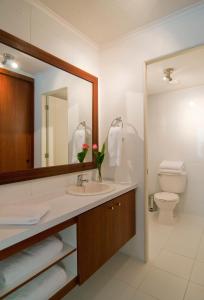 a bathroom with a sink and a toilet and a mirror at Park Plaza Apart Hotel in Santiago