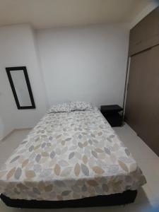 ein Schlafzimmer mit einem Bett mit einer Bettdecke darauf in der Unterkunft Apartaestudio Cartagena in Cartagena de Indias
