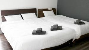 duas toalhas sentadas numa cama com duas camas em MONOCHROME -SEVEN Hotels and Resorts- em Yomitan