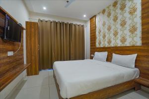 a bedroom with a white bed and a television at FabHotel HC Mohali Inn in Kharar