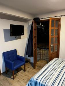 um quarto com uma cama e uma cadeira azul e uma televisão em Casa Dos Fridas - Centro Guanajuato em Guanajuato